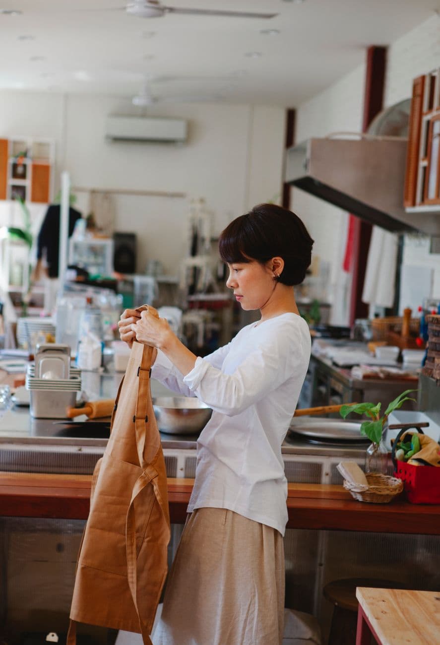 Small business owner tying an apron in her kitchen